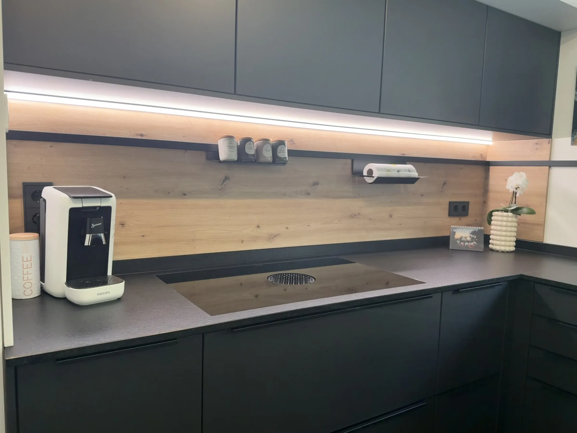 Arbeitsbereich mit Kochfeld, Holzrückwand und Lichtlinie