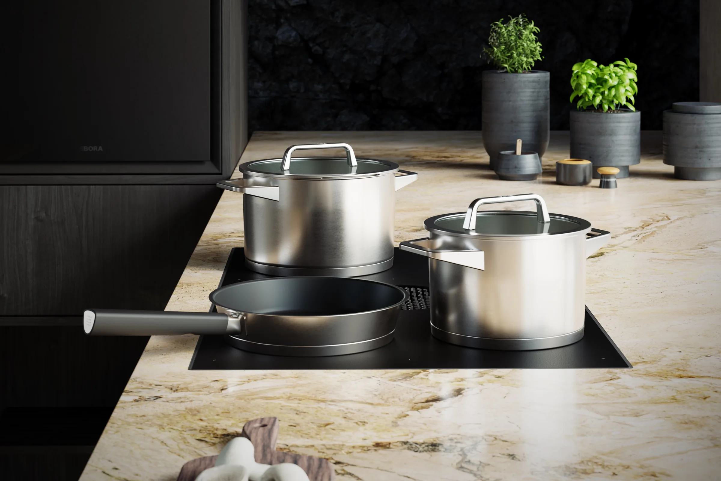 Töpfe und Pfanne von BORA Pots and Pans auf einem BORA Kochfeld in einer Arbeitsplatte aus Naturstein