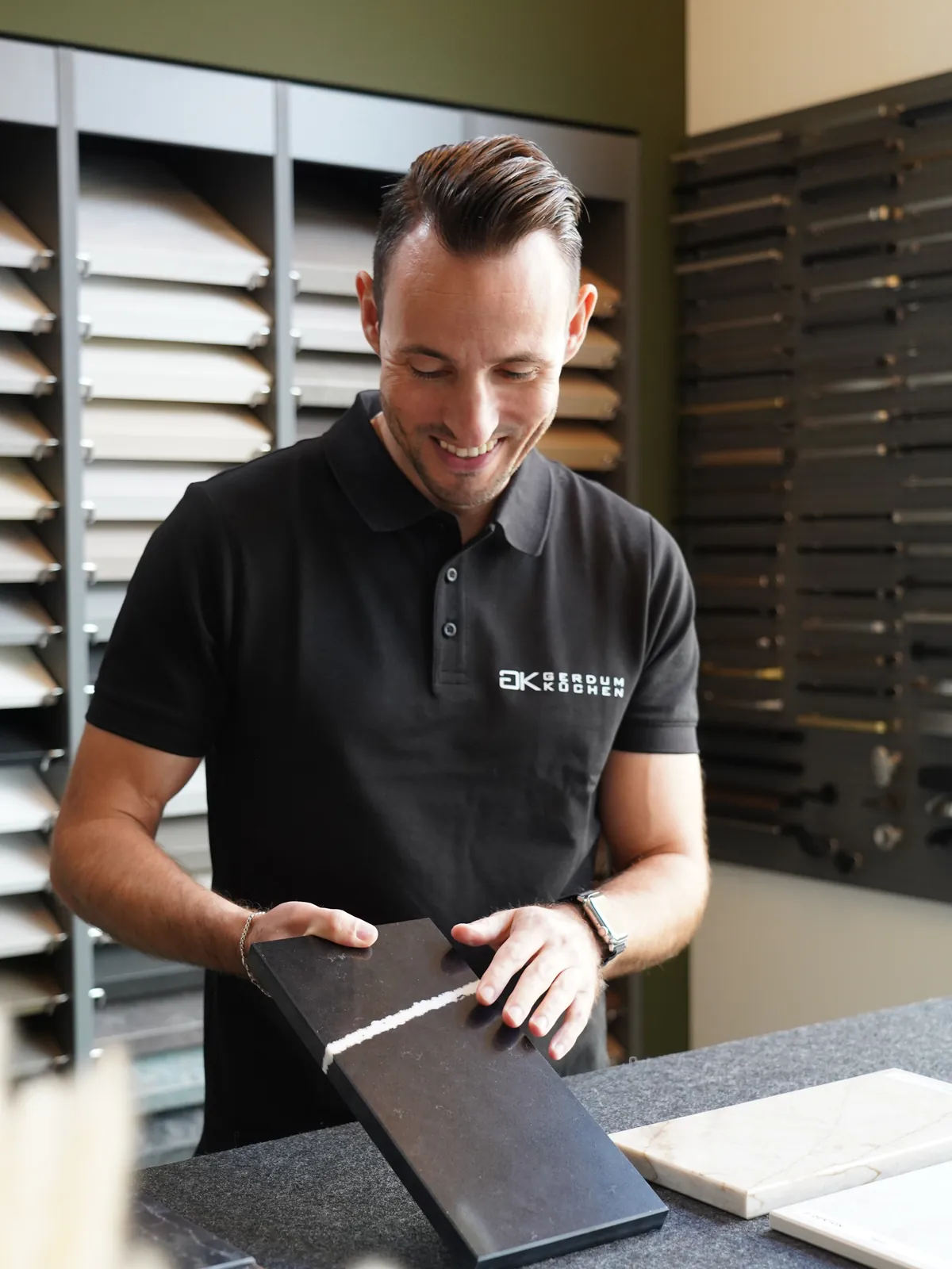 Pascal Gerdum mit einem Arbeitsplattenmuster vor der Musterwand im Showroom
